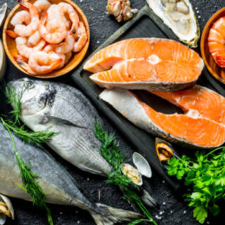 Fresh salmon steak with a variety of seafood and herbs. On black rustic background